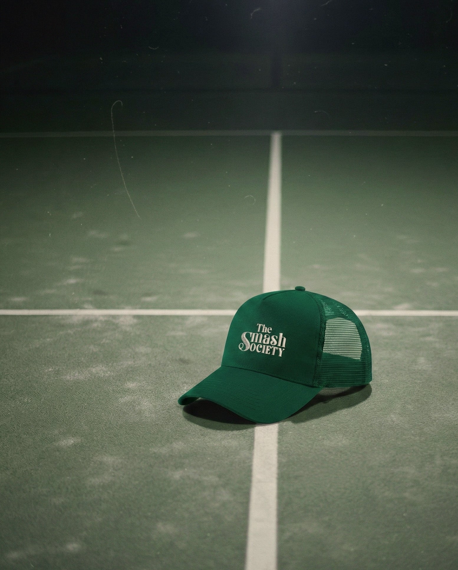 Green cap with 'The Crush Society' logo on a padel court
