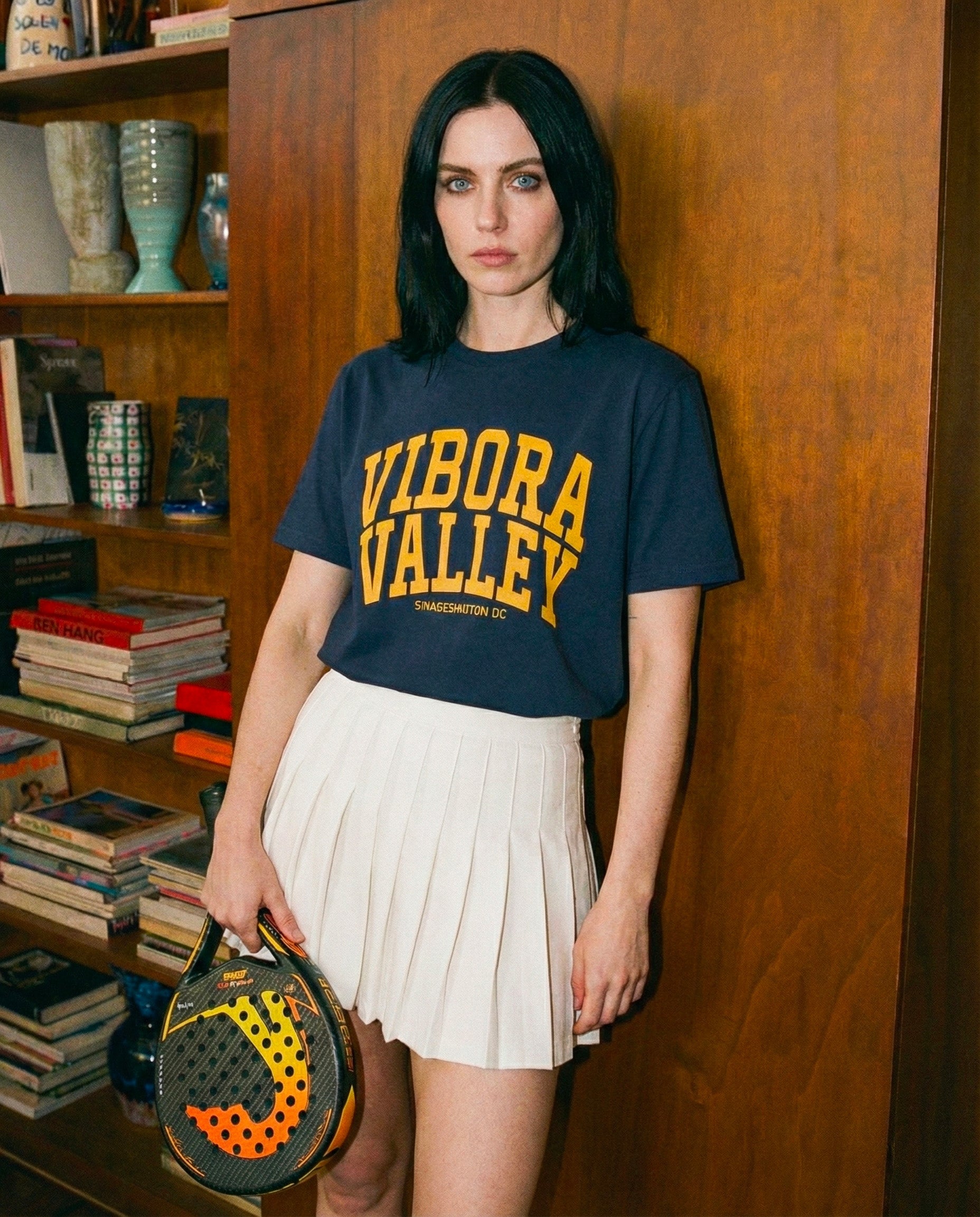 woman wearing a navy padel t-shirt vibora valley and a white padel skirt