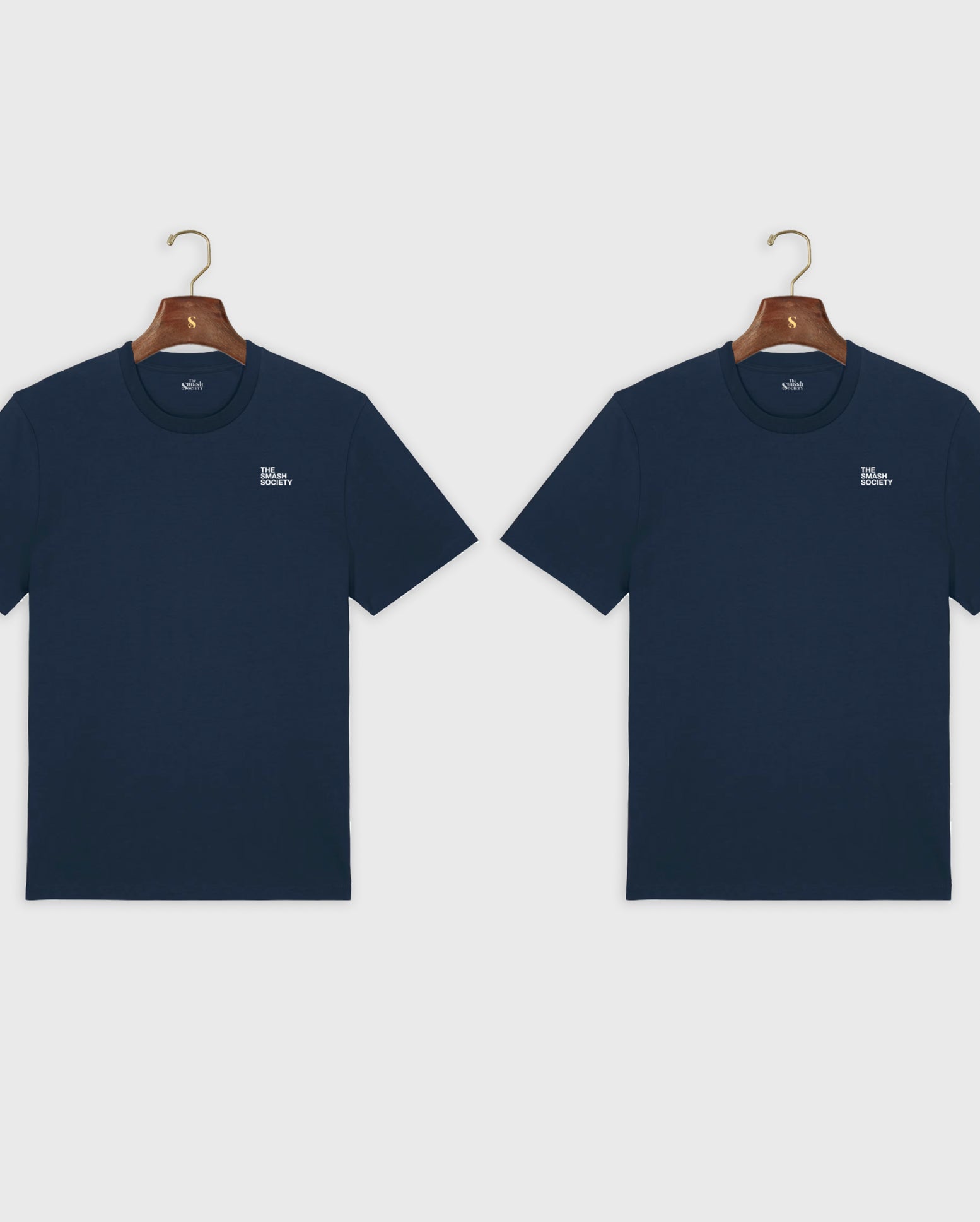 Two navy blue t-shirts the smash society with a small white logo on hangers against a light gray background.