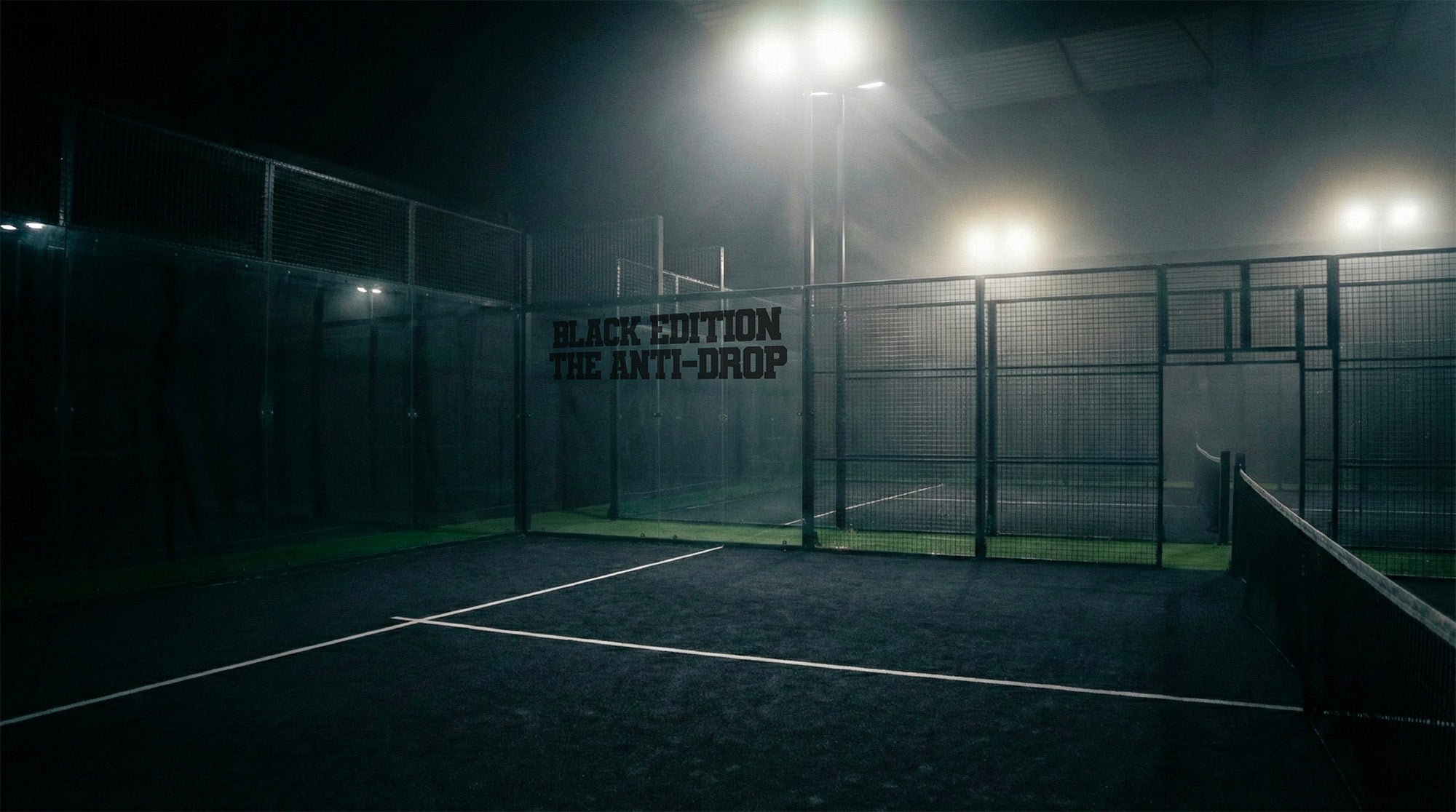 Indoor misty padel court with 'Black Edition The Anti-Drop' branding at night.